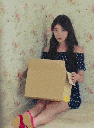 Girl puts a cartoon box on her head to hide.