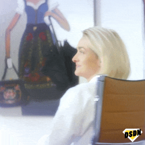 Blond woman winks, turning on her chair.